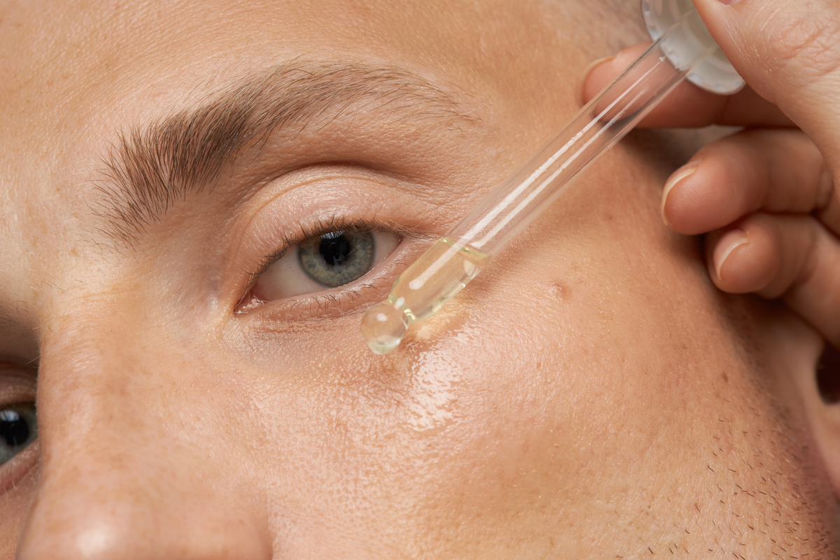 white man applying a dropper of facial oil to their eye area, bearpo all in one facial oil the glow